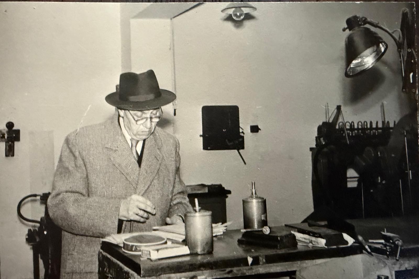 Karl-Josef Luthe mit Hut und Mantel an einer Maschine in der Druckerei, Schwarz-Weiß-Foto